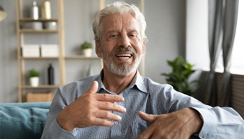 An older man speaking with dentures