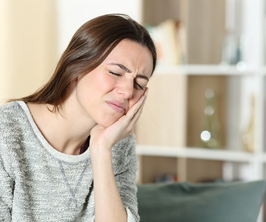 Close-up of woman rubbing her jaw due to discomfort