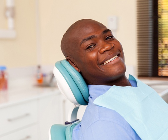 Man leaning back in dental chair and smiling