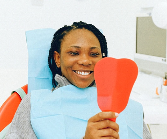 Woman at dentist looking in hand mirror