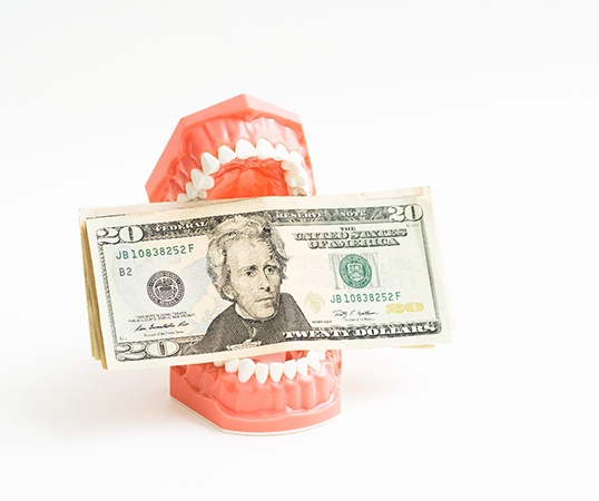Dentures holding money representing cost of dentures in Mesquite 