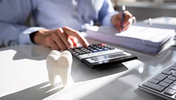 Mesquite dentist calculating cost of dentures with model tooth
