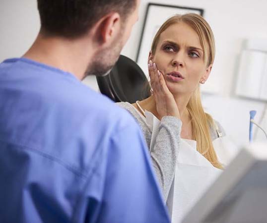 Dentist answering questions about woman’s dental emergency in Mesquite