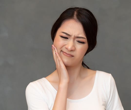 person holding their mouth due to wisdom tooth pain