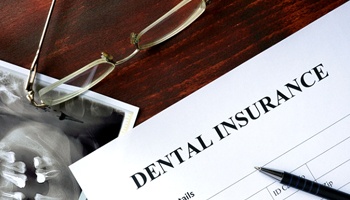 Dental insurance form with glasses, pen, and X-Ray