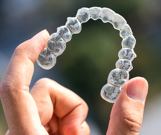 person holding up an Invisalign aligner