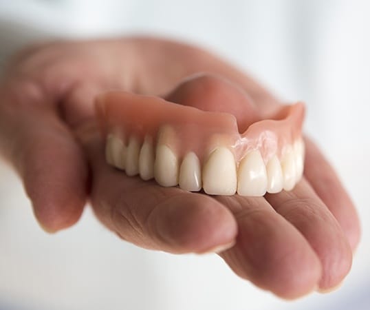 Hand holding a full set of dentures