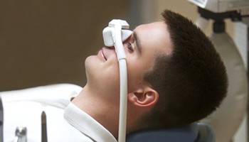 man in dental chair wearing nitrous oxide mask