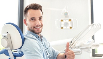 man giving thumbs up in dental chair