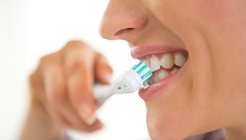 closeup of young woman brushing teeth