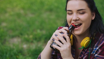 woman opening bottle with mouth