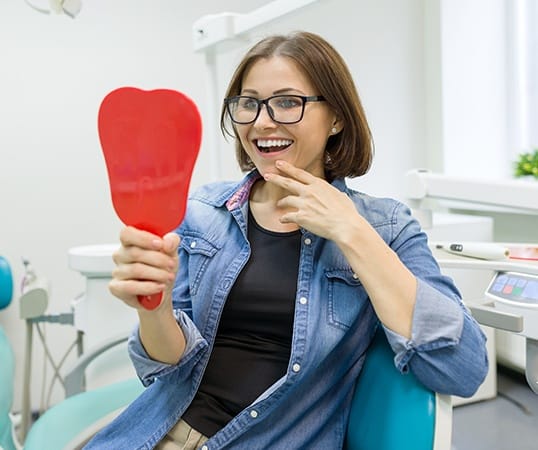 Woman with one visit dental restoration looking at smile in mirror