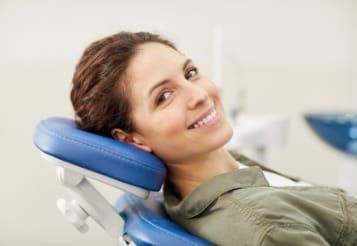 Woman in dental chair smiling after preventive dentistry