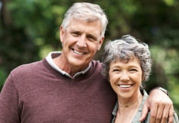 Older man and woman smiling after restorative dentistry