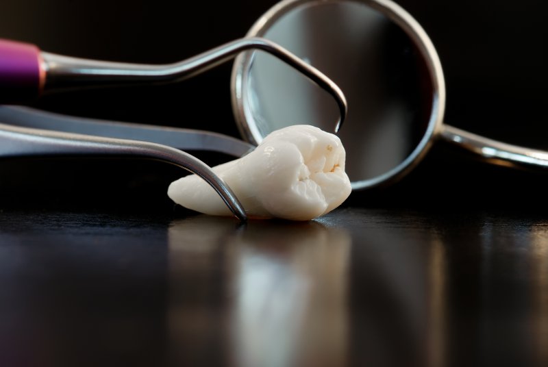 an extracted tooth lying on a table surrounded by dental instruments