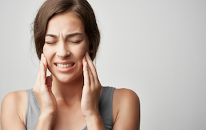 woman experiencing dental pain, grimacing, white background