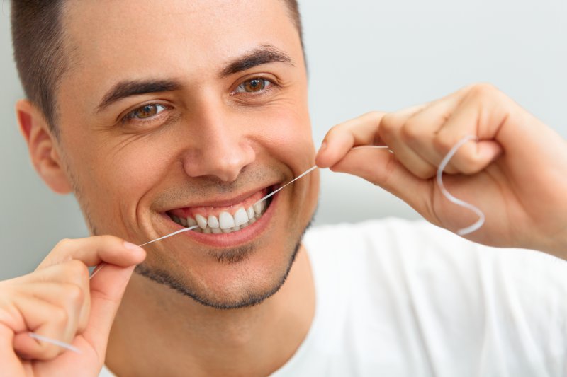 man flossing his teeth