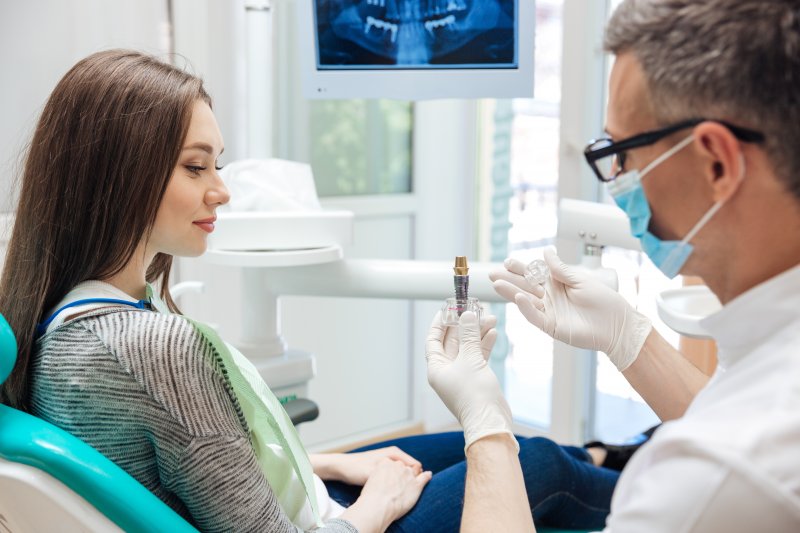 Smiling patient looking at dental implant model