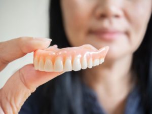 woman holding replacement dentures