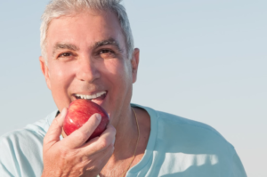 a patient with dentures biting into an apple 