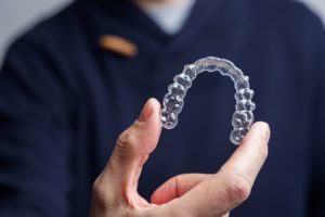 Man holding an Invisalign tray that has bumps for attachments